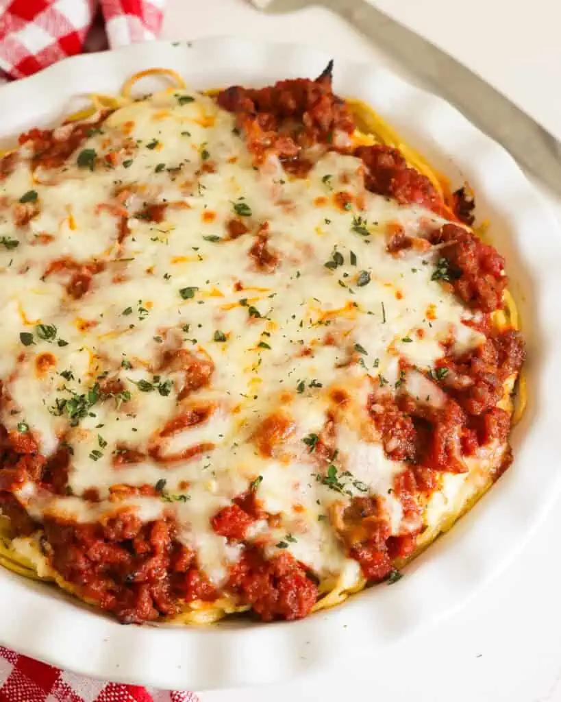 Baked spaghett pie topped with melted chese in a pie plate 