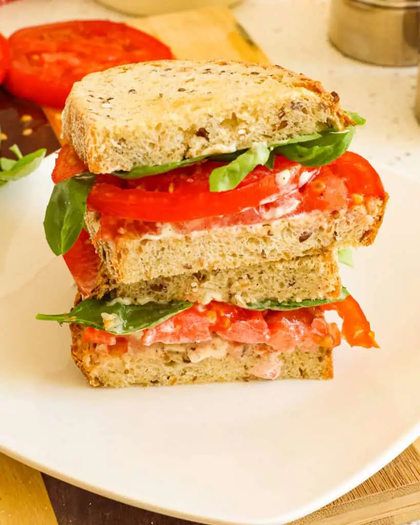 A tomato sandwich stacked on a plate. 
