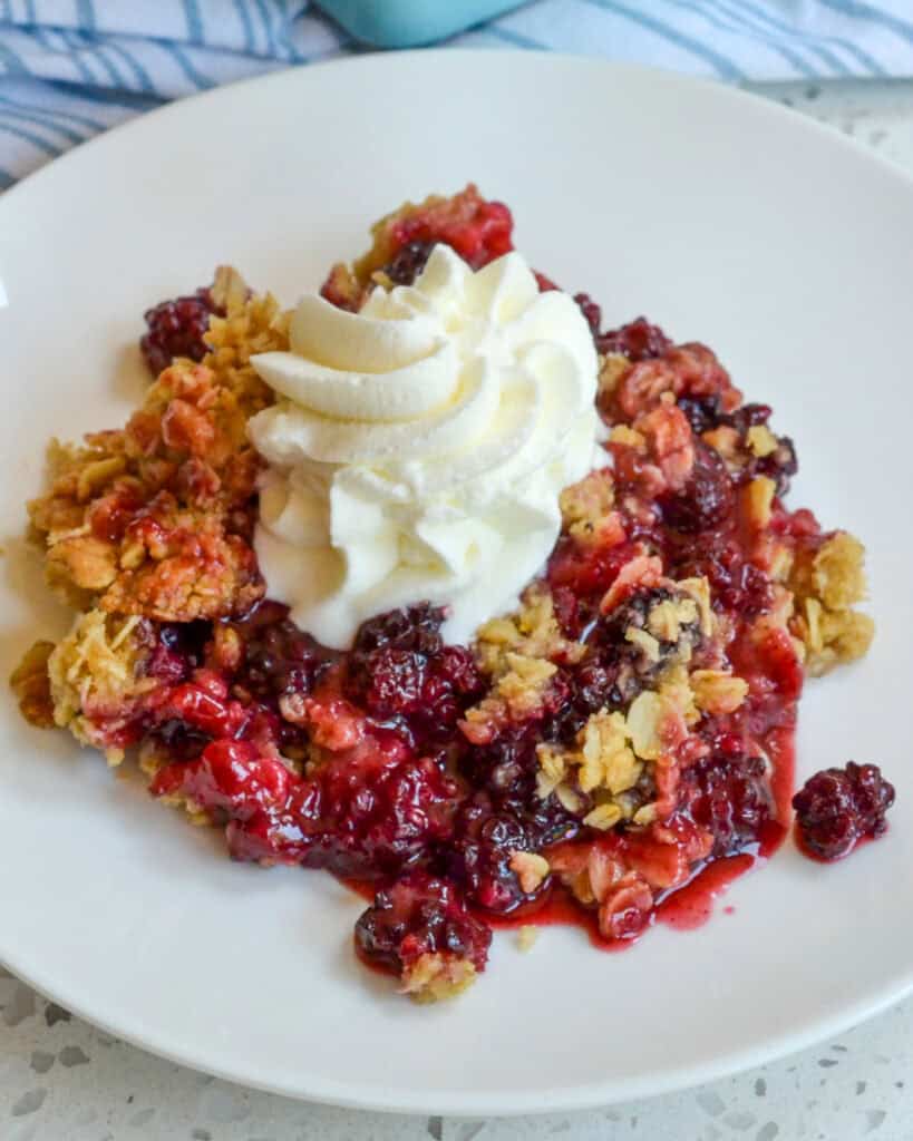 Blackberry Crisp on a plate with whipped cream.