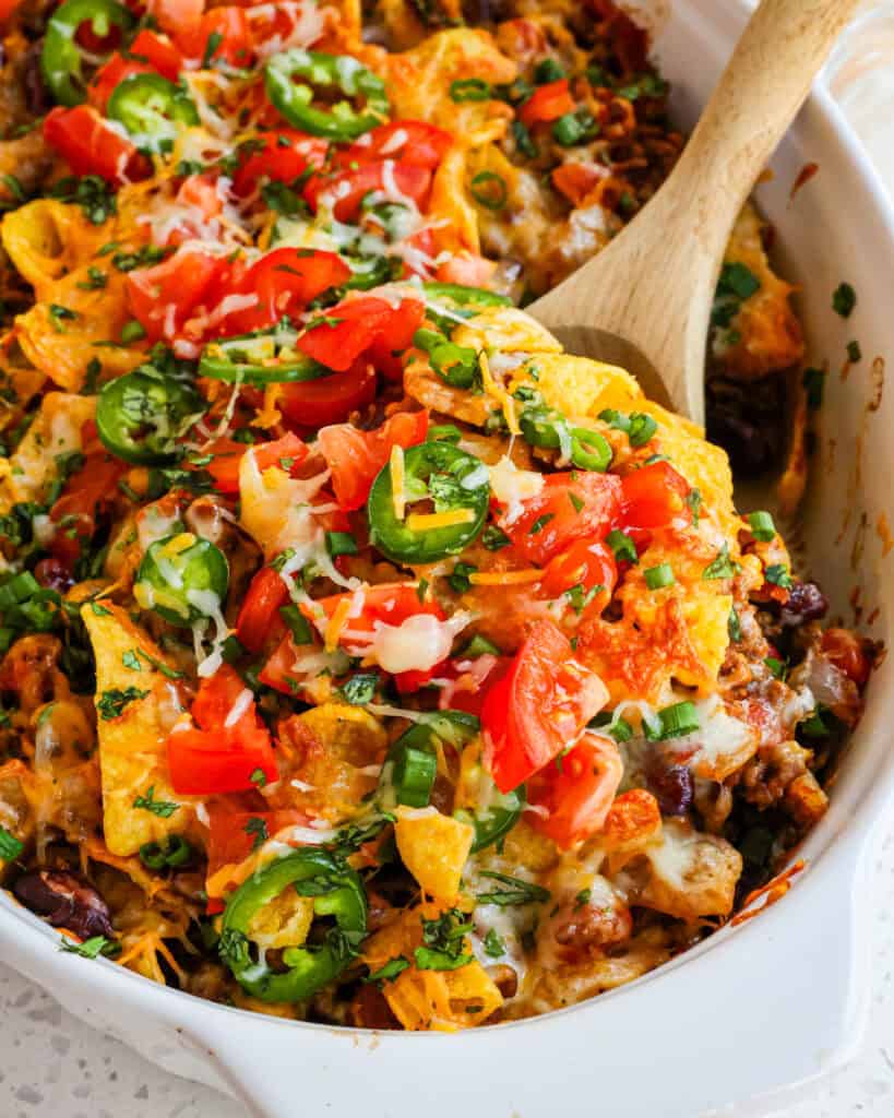 A big spoonfull of Frito pie topped with tomatoes, jalapeno, and green onion