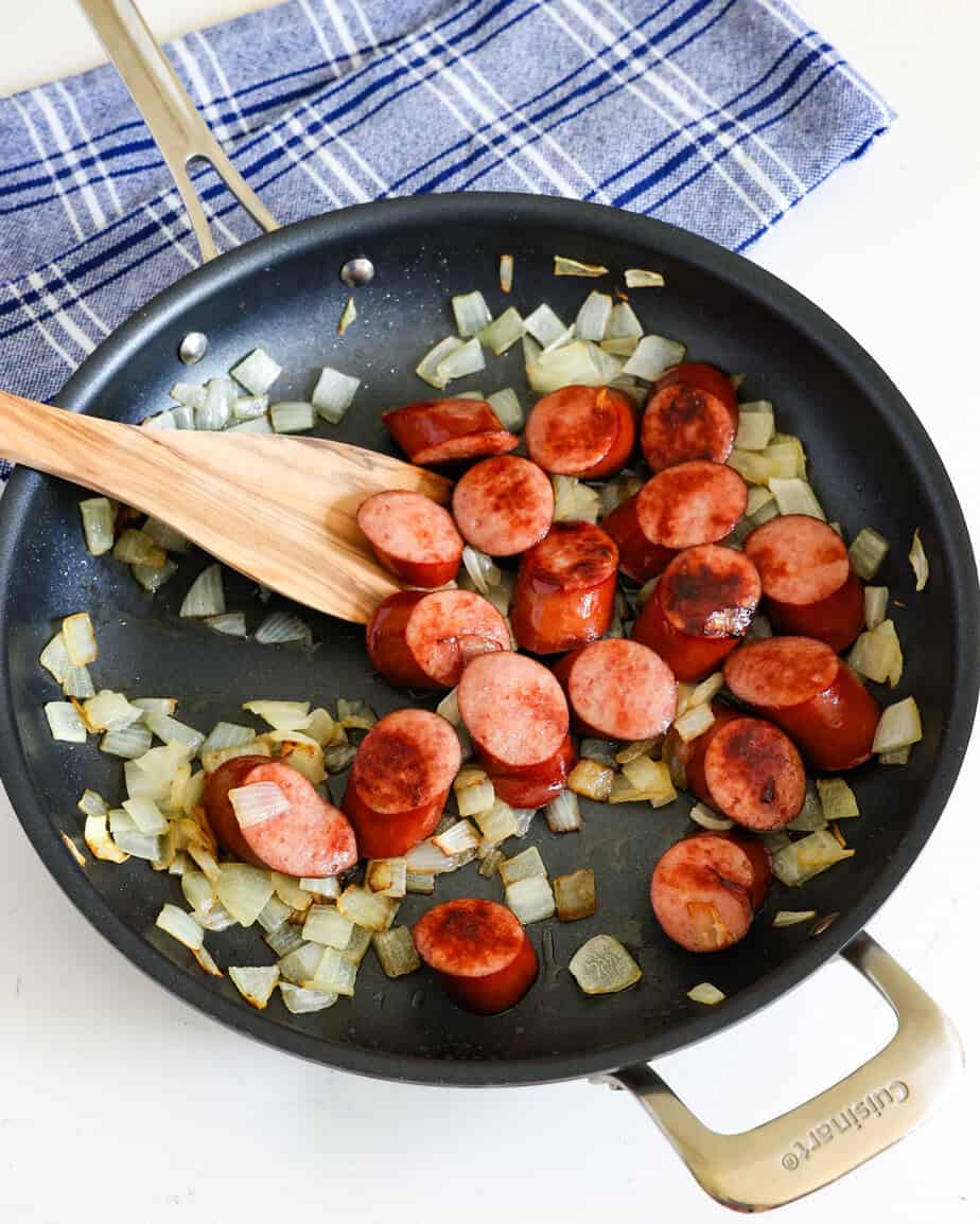 In a large skillet, heat vegetable oil over medium heat. Toss in the onion and sausage. Cook until the onion is soft and the sausage is browned.