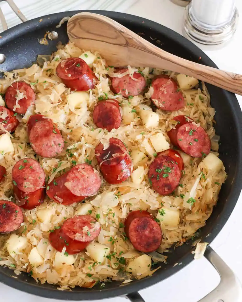 Polska kielbasa and sauerkraut cooked in large skillet. 