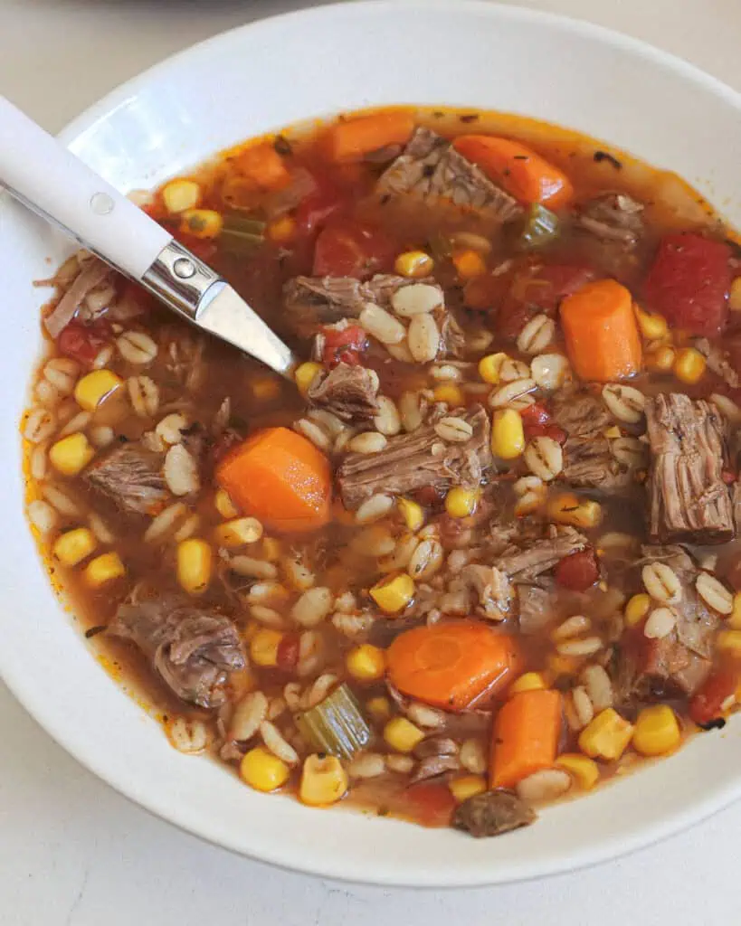 A close up view of beef barley soup in a bowl. 