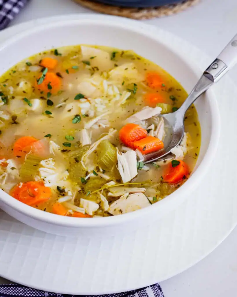 A bowl and a spoon full of chicken and rice soup.