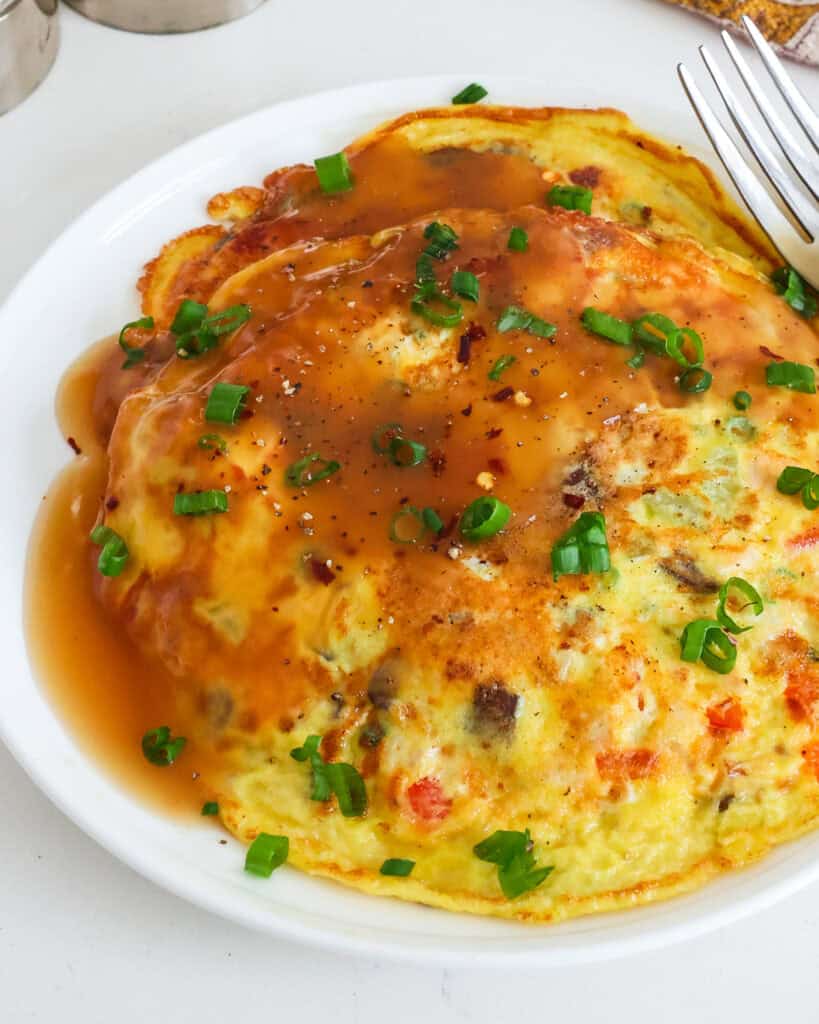 A close up view of egg foo young on a plate with a fork. 