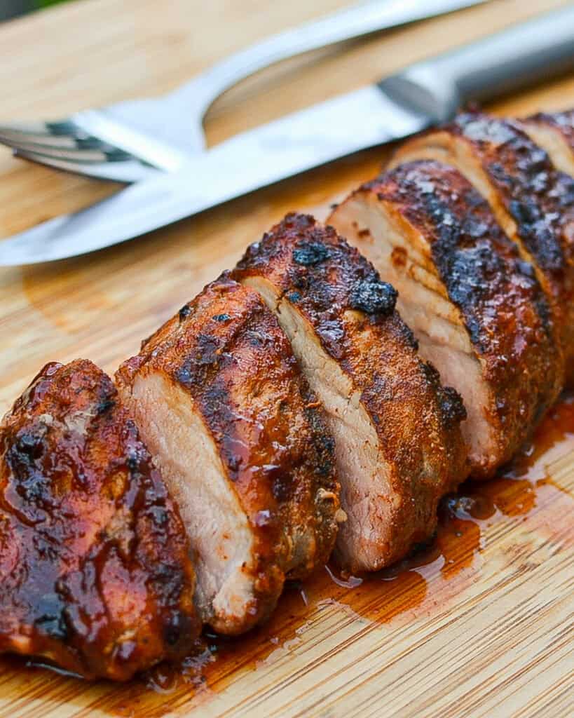 Grilled Pork Tenderloin Grilled Pork Tenderloin sliced on a cutting board.