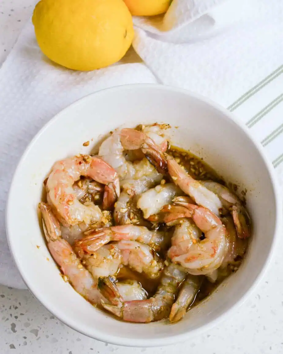 Shrimp marinating in a medium bowl. 