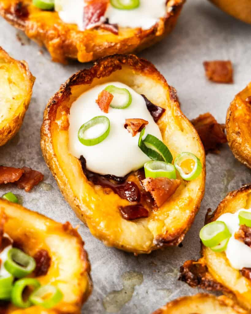 A close up view of a potato skin on a baking sheet with other potato skins in the background. 