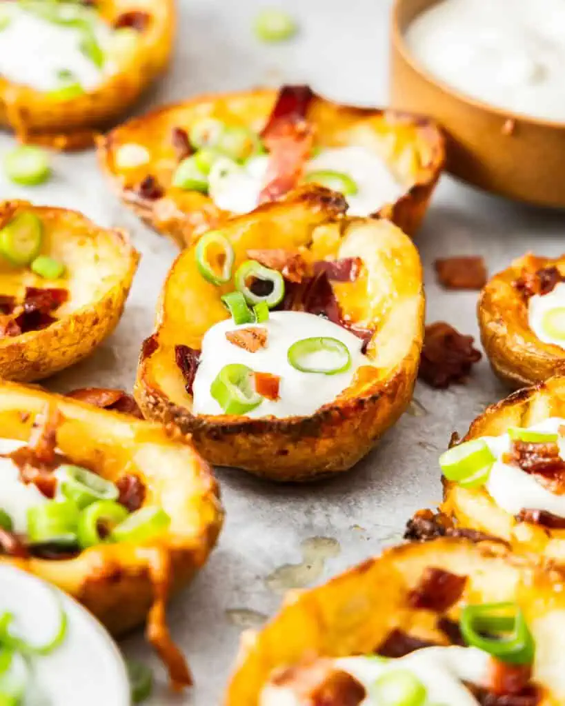 Cheesy potato skins with green onions, sour cream, and crisp bacon. 
