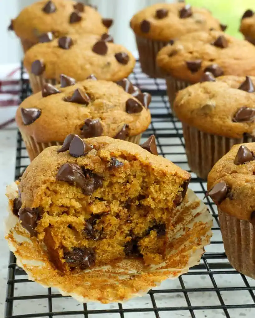 A pumpkin chocolate chip muffin cut in half on a cooling rack.