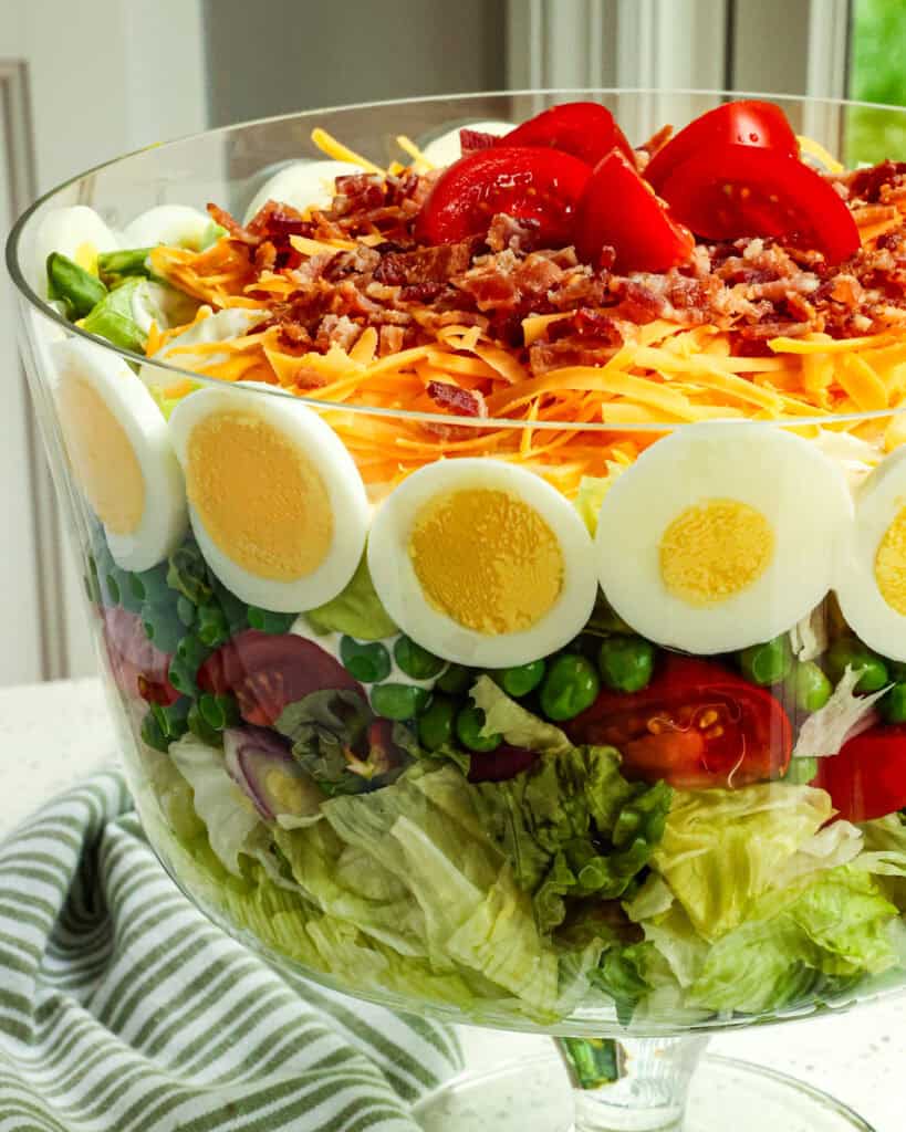 Seven layer salad in a trifle bowl.