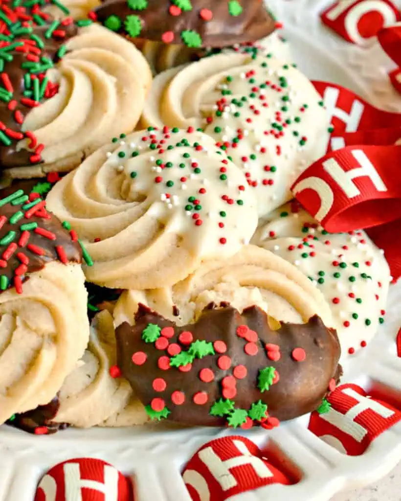 A close up view of butter cookes dipped in white and semi-sweet chocolate with Christmas sprinkles. 