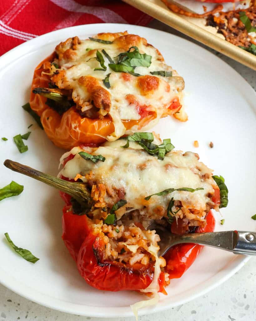 Baked stuffed bell peppers on a serving plate with a fork.
