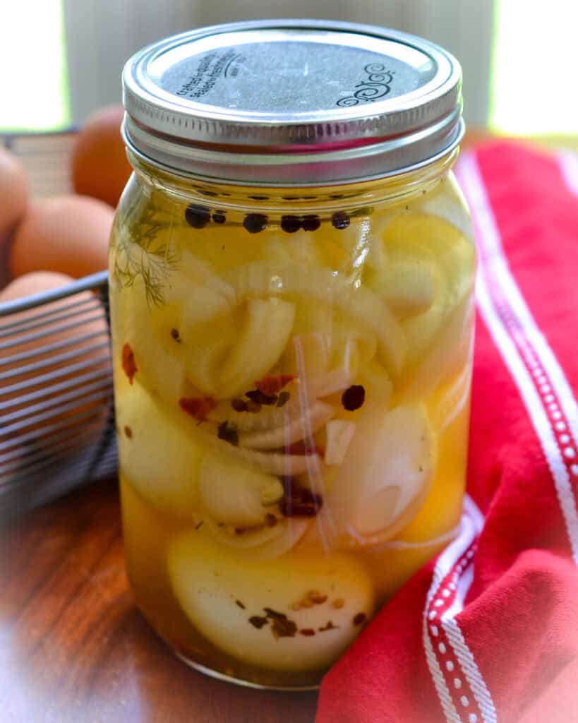 Pickled Eggs Pickled eggs in a large mason jar with fresh eggs in the background.