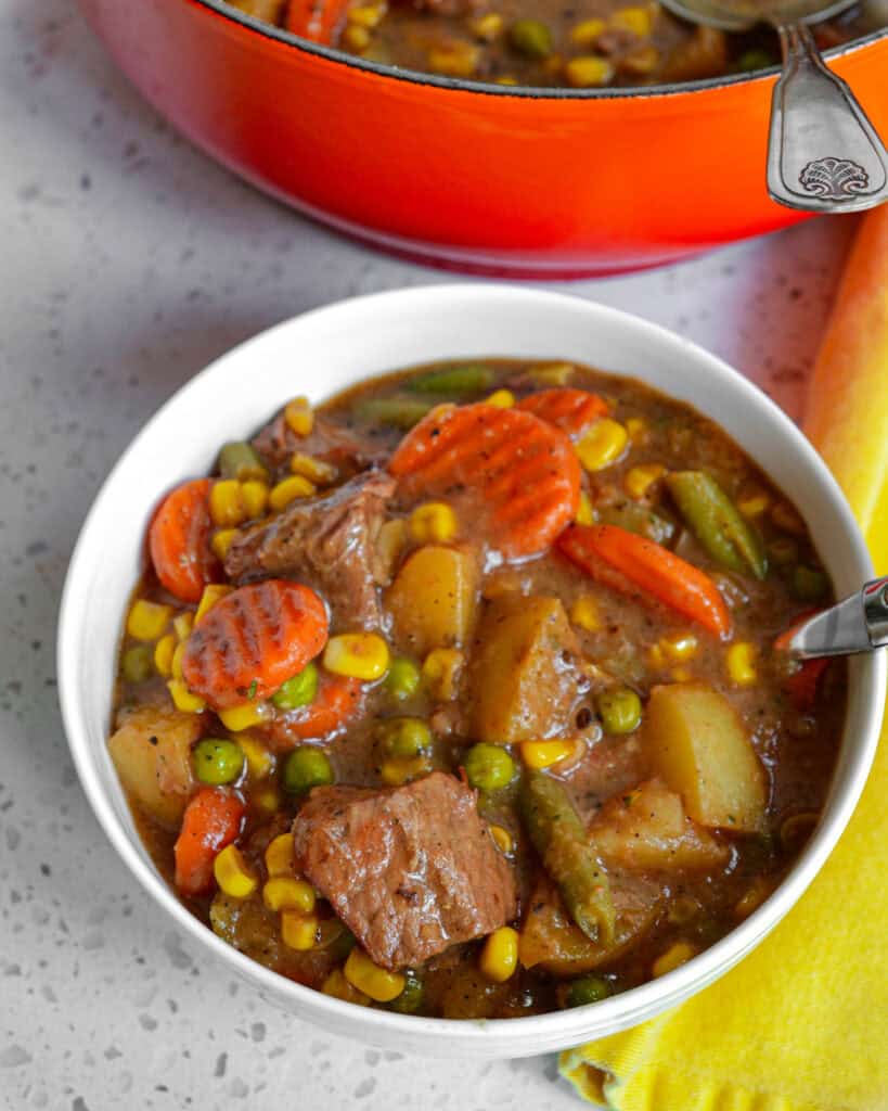 Mulligan Stew Recipe A bowl full of Mulligan stew tender stew meat, potatoes, corn, carrots, peas, green beans, and a perfect blend of spices.