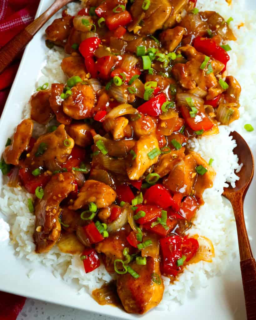 Pepper chicken over white rice on a serving platter. 