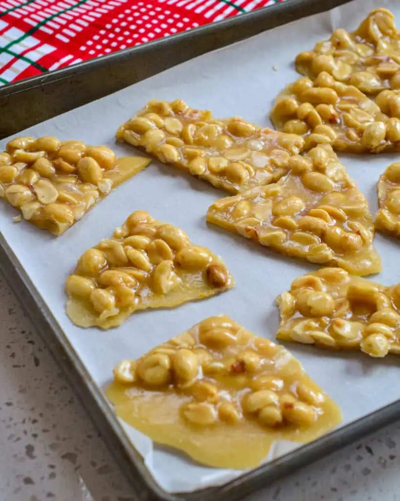 Peanut brittle pieces on a baking sheet covered with parchment paper.
