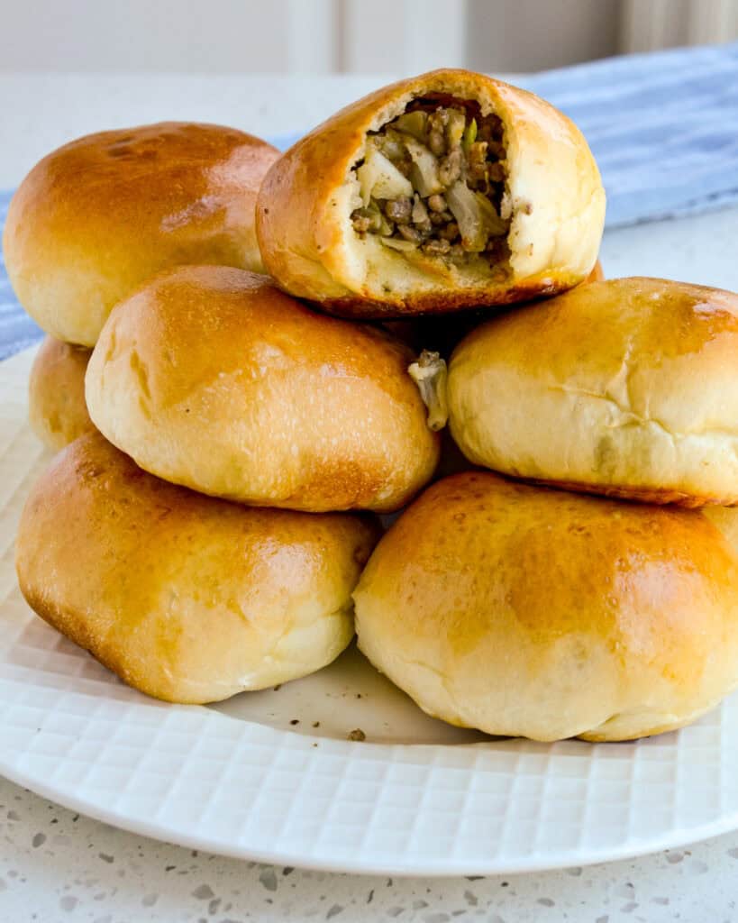 Runzas stacked on a plate with a bite taken out of one of them. 