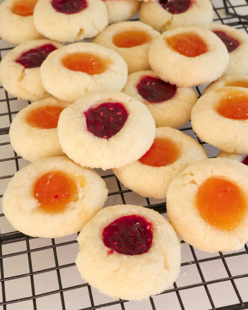 Close up view of raspberry and apricot thumbprint cookies on a cooling rack. 