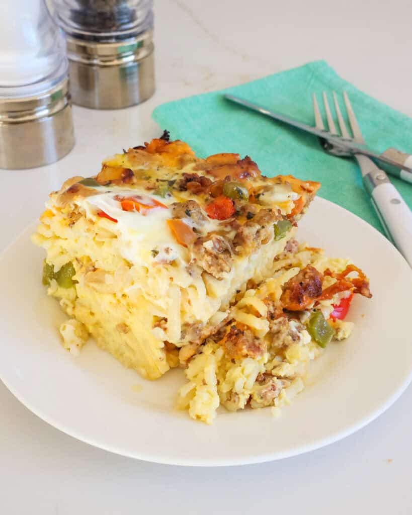 A piece of crock pot egg casserole on a single serving plate with salt and pepper shakers in the background. 