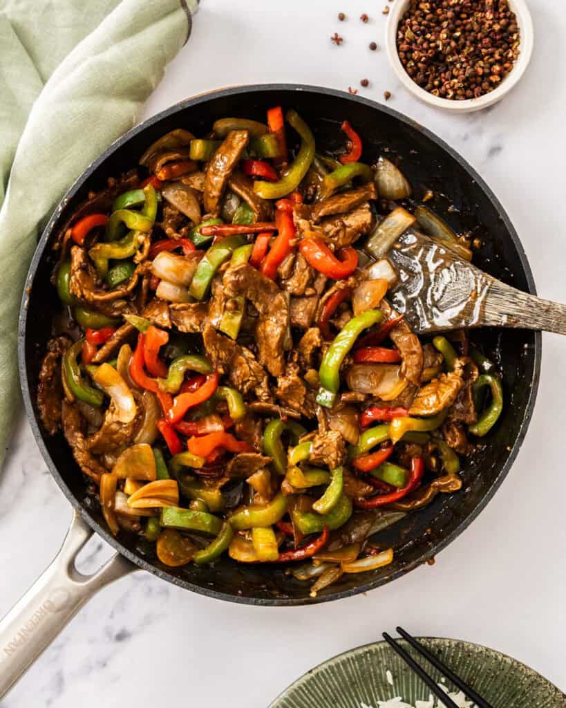 An overhead view of a black skillet full of szechuan beef .