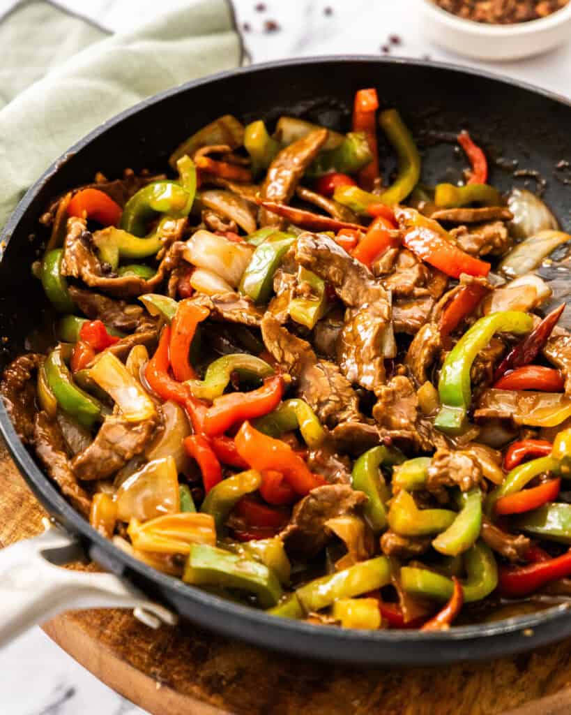 A close up view of beef szechuan beef in a black skillet.