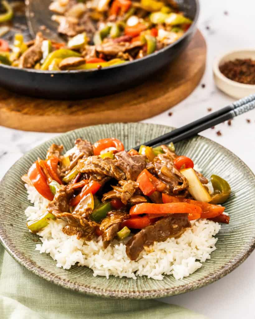Szechuan beef over white rice on a single serving plate.