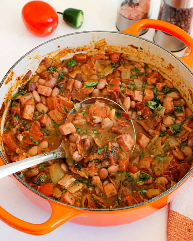A Dutch oven full of charro beans which is pinto beans, bacon, onion, jalapeno pepper, an tomatoes in a perfect blend of spices.
