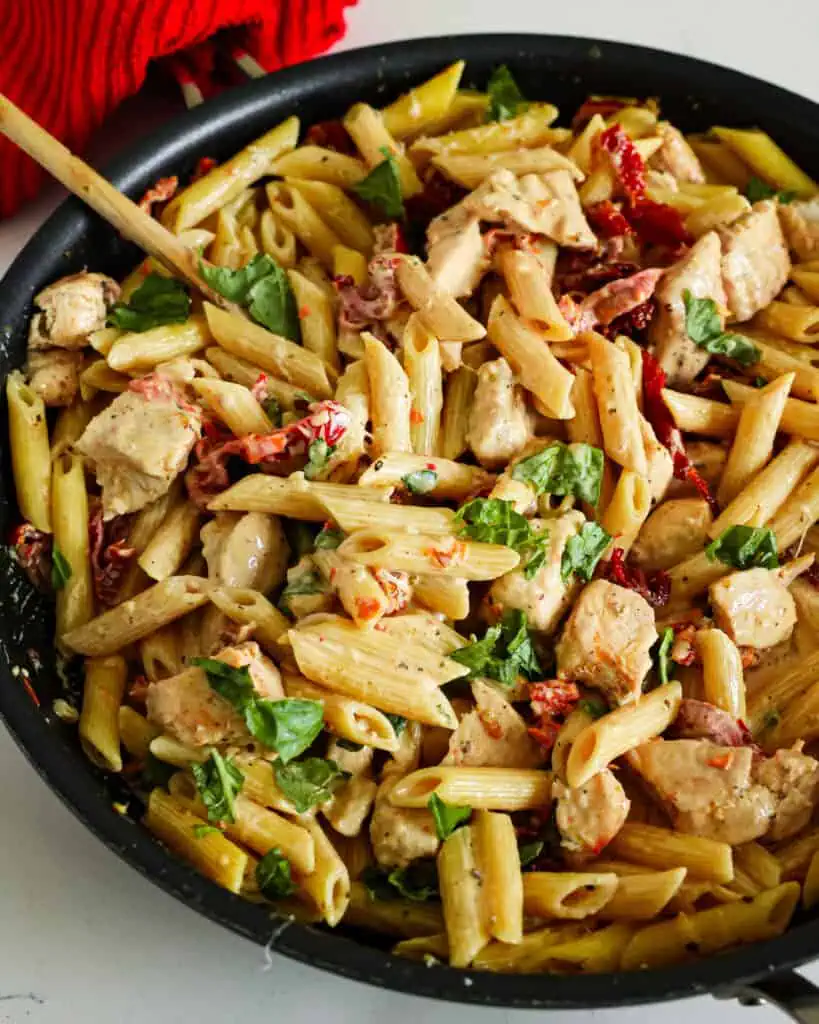 A close up view of Marry Me Chicken in a large skillet with a wooden spoon. 
