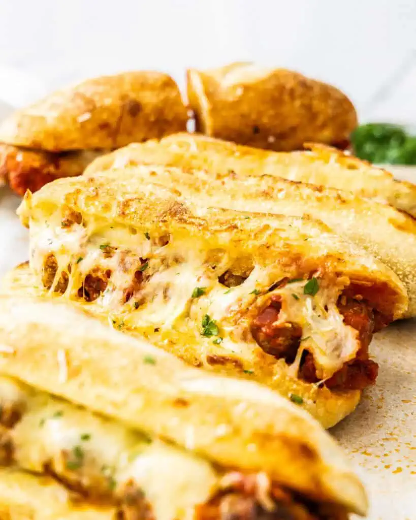 A close up view of meatball subs with toasted buns and melted mozzarella cheese.