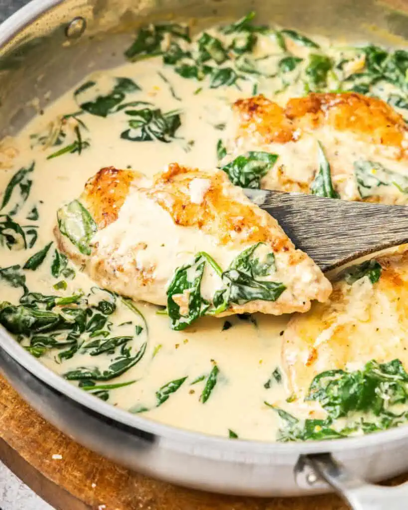 A skillet full chicken floretine and a close up view of a piece of chicken florentine on a wooden spatula.