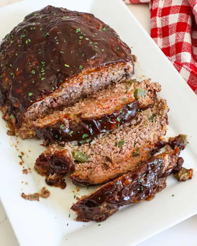 An overhead view of Cracker Barrel meatloaf with a couple of slices cut on a white serving platter. 