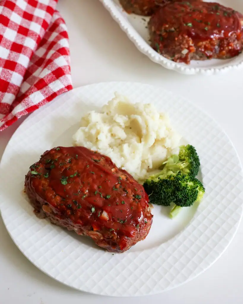 An overhead view of a serving plate with mini meatloaf, mashed potatoes, and broccoli. 