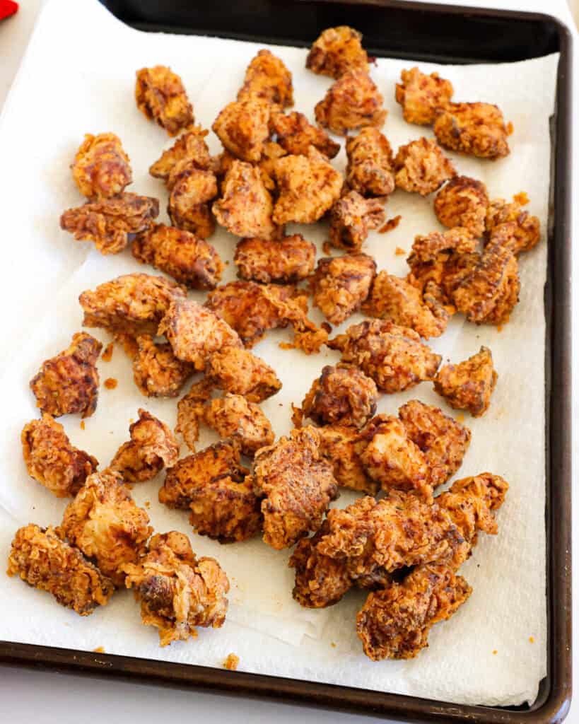 Fried popcorn chicken on a baking sheet covered with paper towels. 