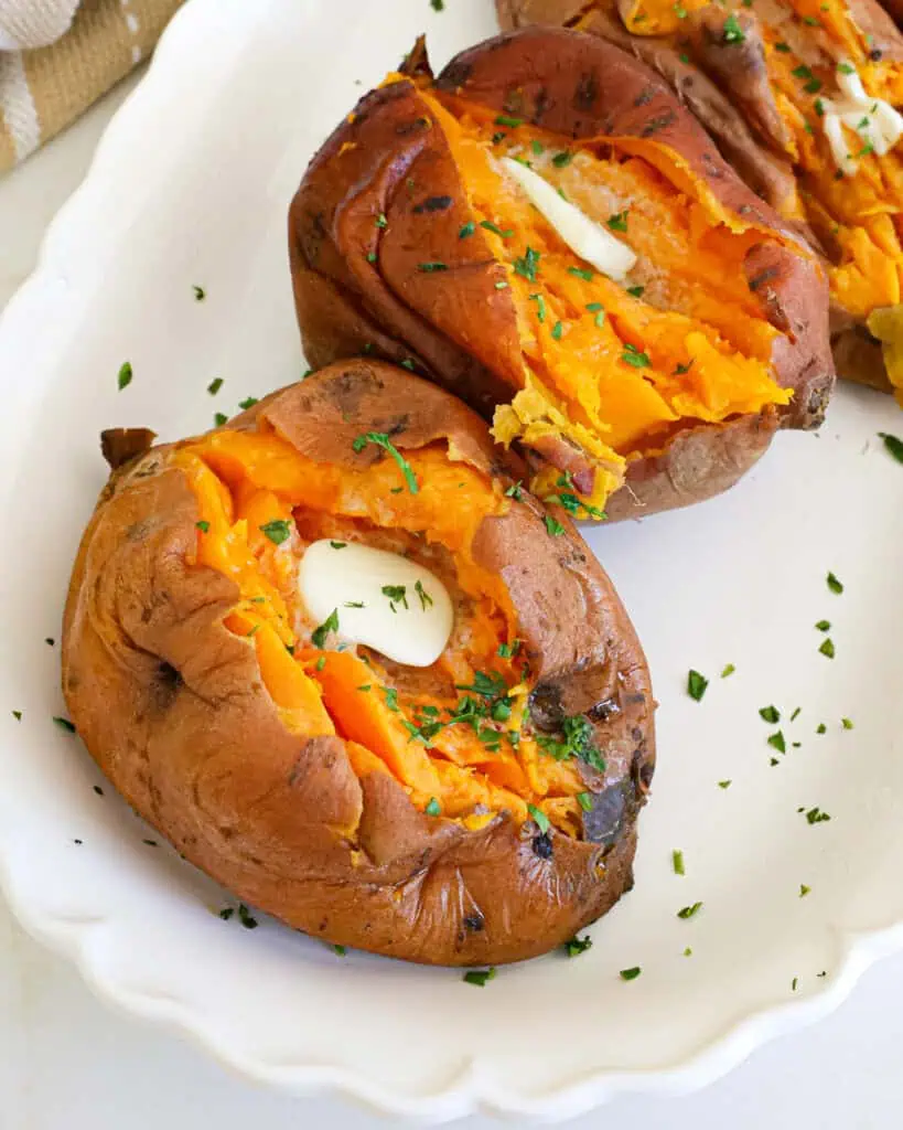 Instant pot sweet potatoes with butter and chopped parsley on a serving platter. 