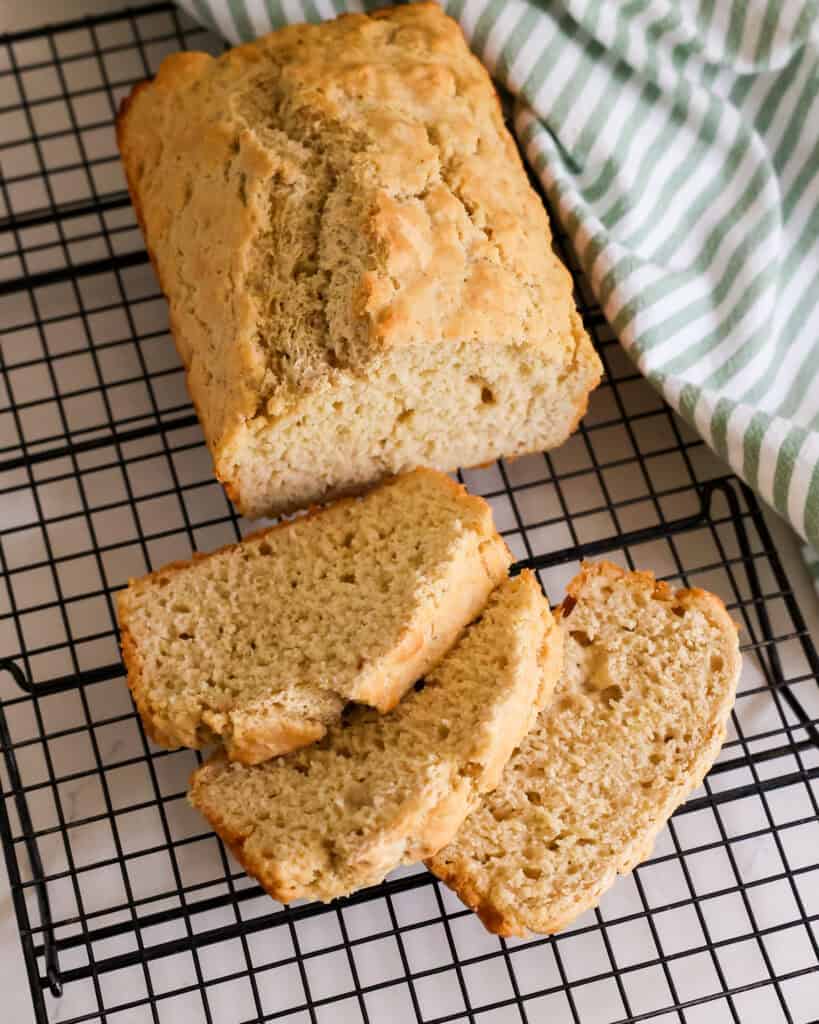 A loaf of beer bread sliced on a cooling rack. 