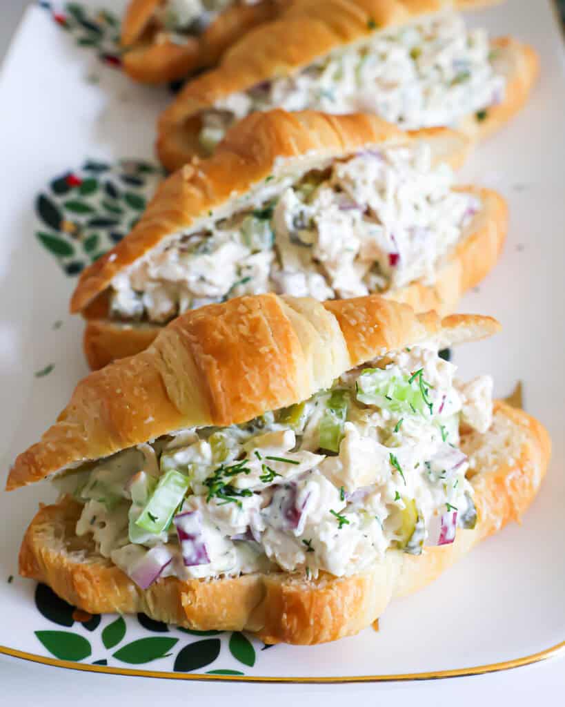 A close up view of a dill pickle chicken salad on a white platter. 