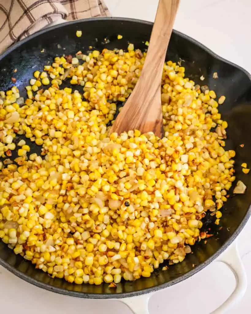 A cast iron skillet full of fried corn.