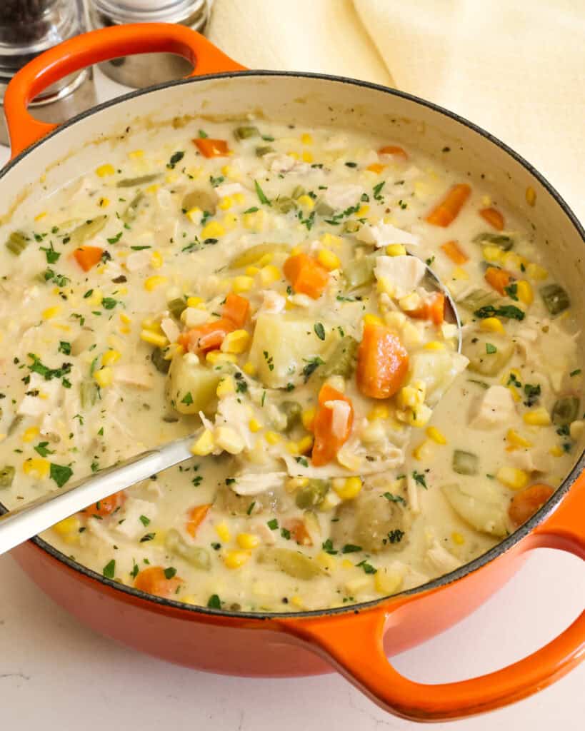 A big orange Dutch oven full of chicken corn chowder. 