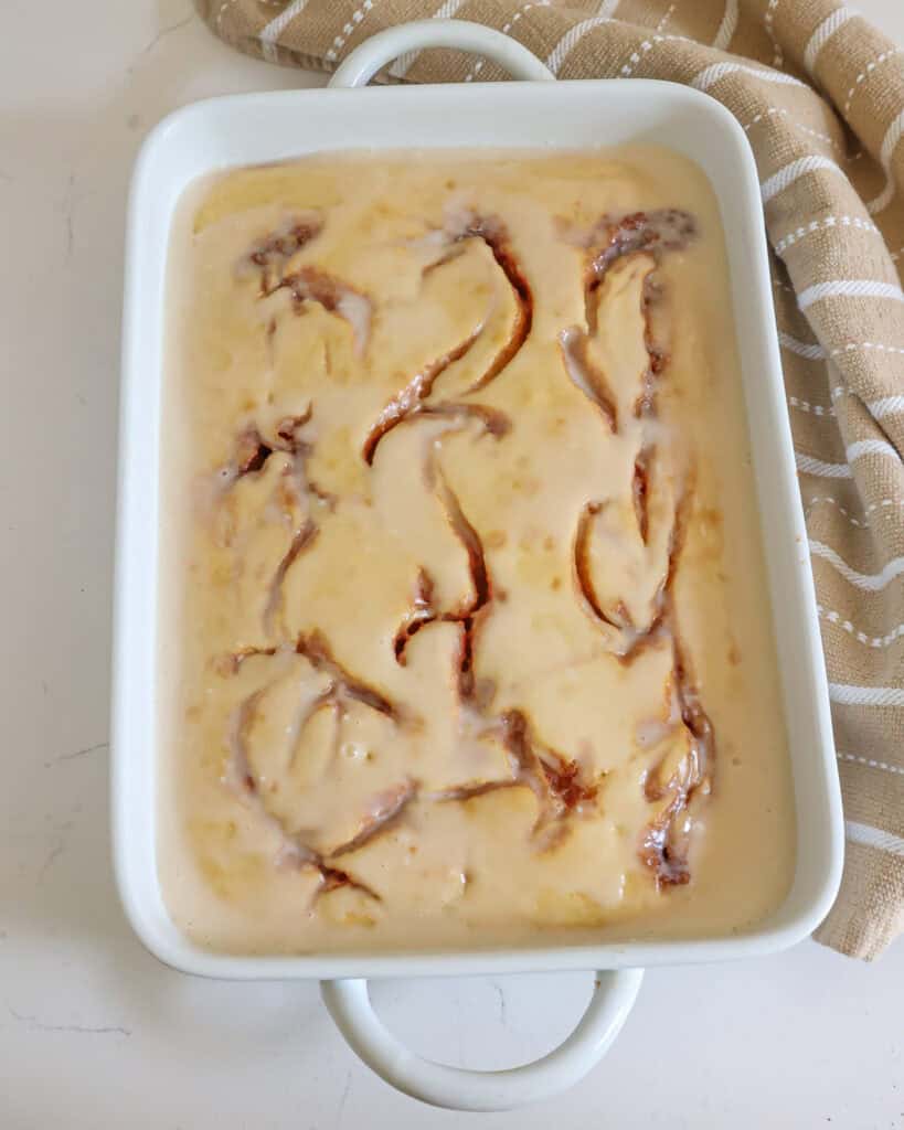 An overhead view of a cinnamon roll cake in a white 9x13-inch baking dish. 