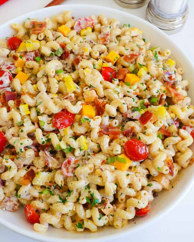 A close up view of cowboy pasta salad in a large white serving bowl.