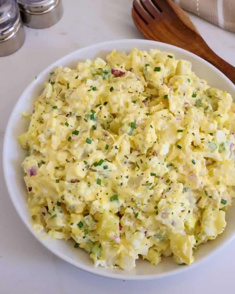 A large white serving bowl of deviled egg potato salad.