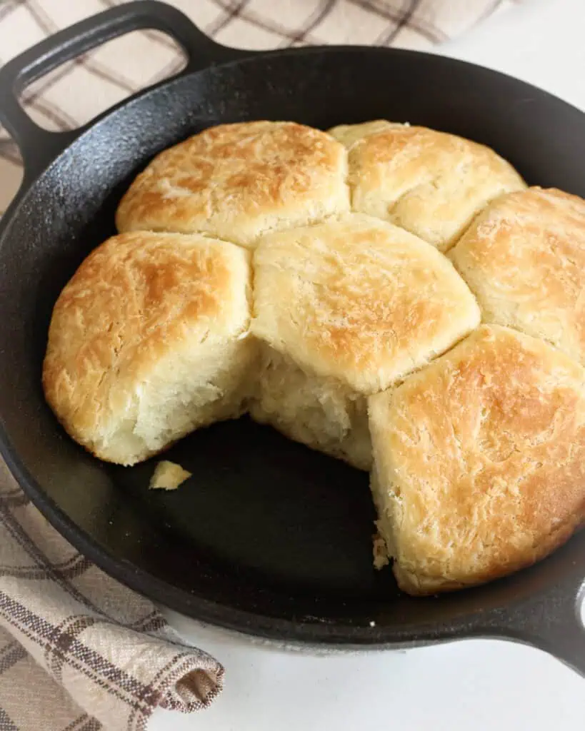 An 8 inch cast iron skillet with 6 angel biscuits in it.