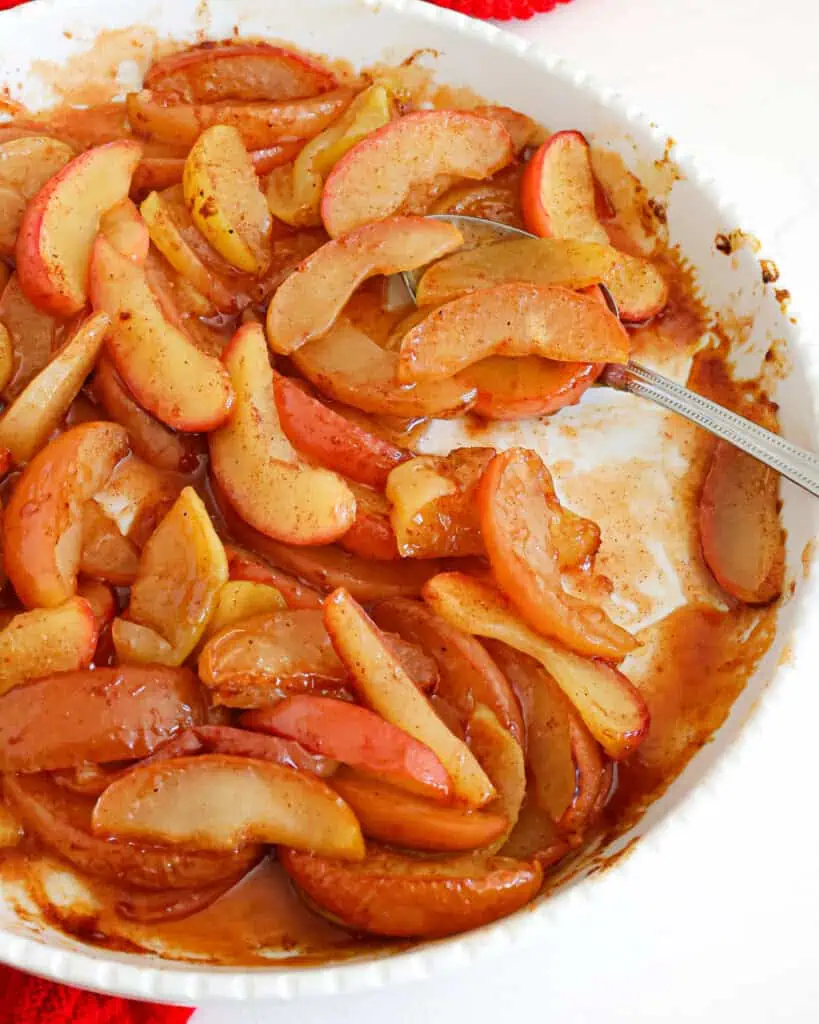 A round white circular baking dish full of baked apples.