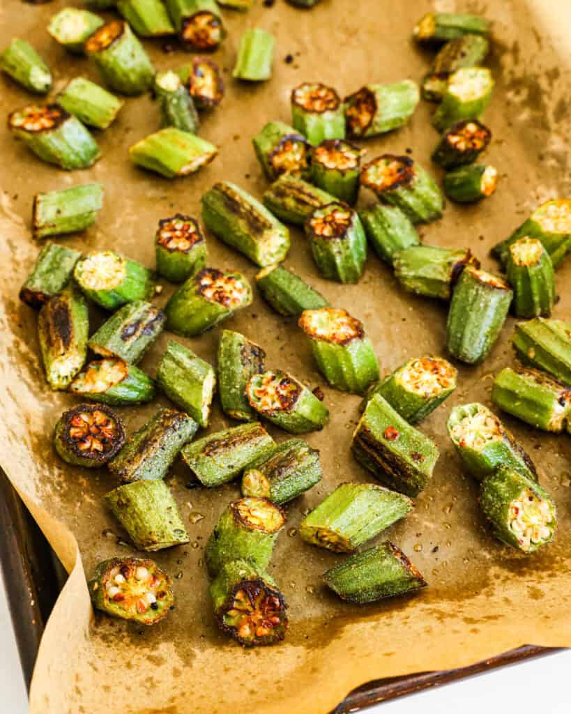 Roasted okra on a parchment-paper covered baking sheet.