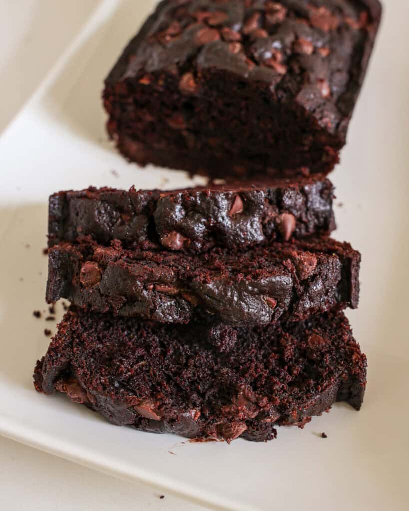 Three slices of chocolate zucchini bread on a white platter.