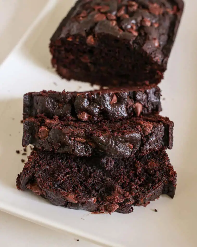 Three slices of chocolate zucchini bread on a white platter. 