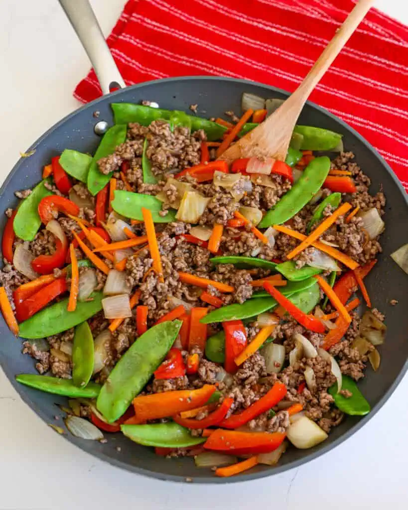 Overhead view of a large black skillet full of ground beef stir fry.