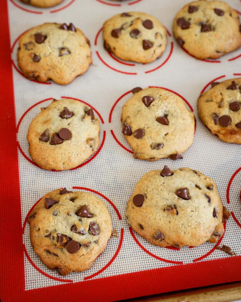 Baked banana chocolate chip cookies on a baking sheet covered with a silicone mat. 
