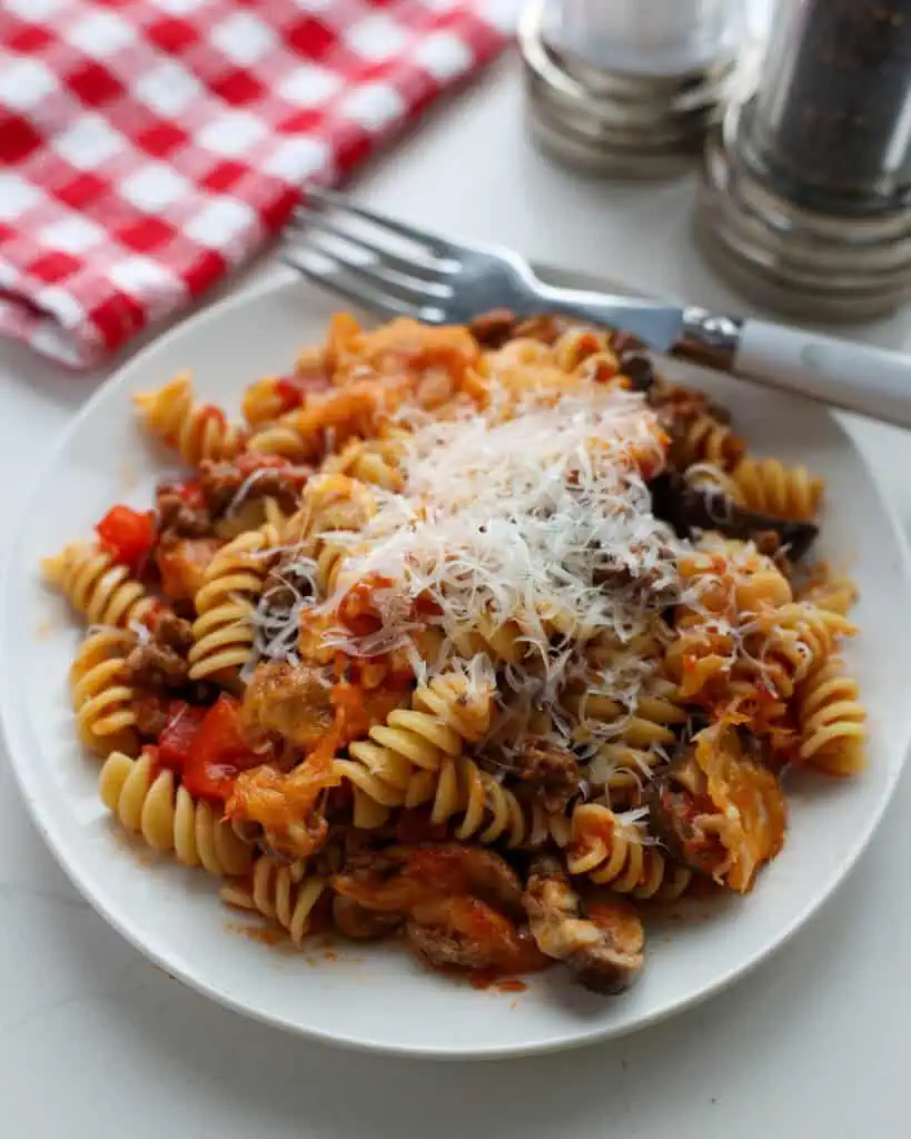 A single serving plate full of Johnny Marzetti casserole with a salt and pepper shaker in the background.